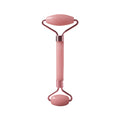 Pink facial roller on a white background