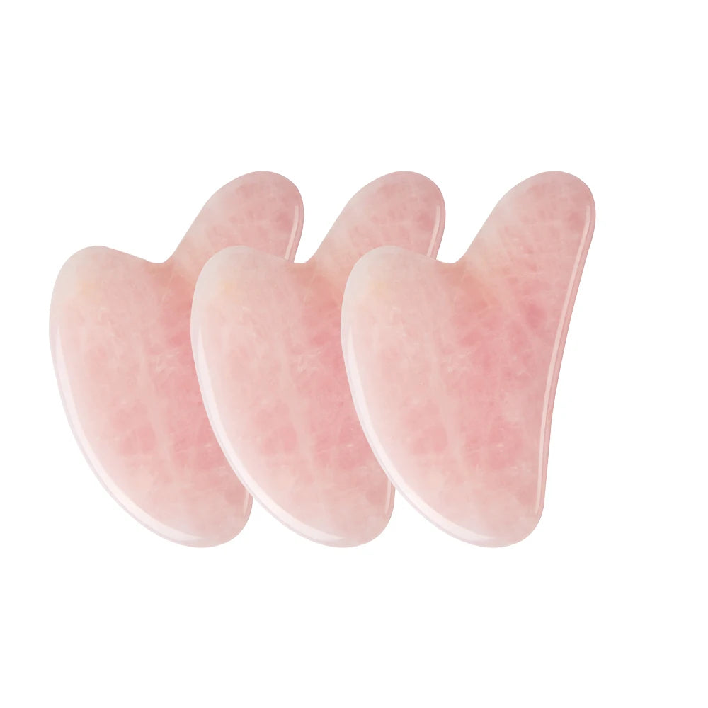 Three rose quartz gua sha tools on a white background