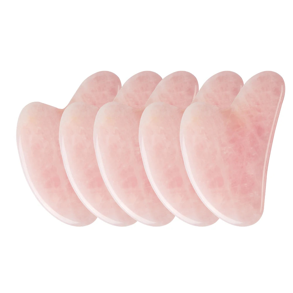 Set of five rose quartz gua sha tools on a white background